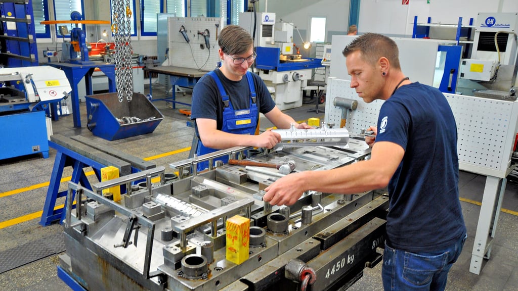Leon Szurawitzki (links) arbeitet gemeinsam mit Ausbilder Sebastian Mergner in der Werkstatt der Umformtechnik Stendal an einem Werkzeug. In eine Presse eingesetzt, stanzt es Metallteile für beispielsweise Autos oder Heizgeräte.