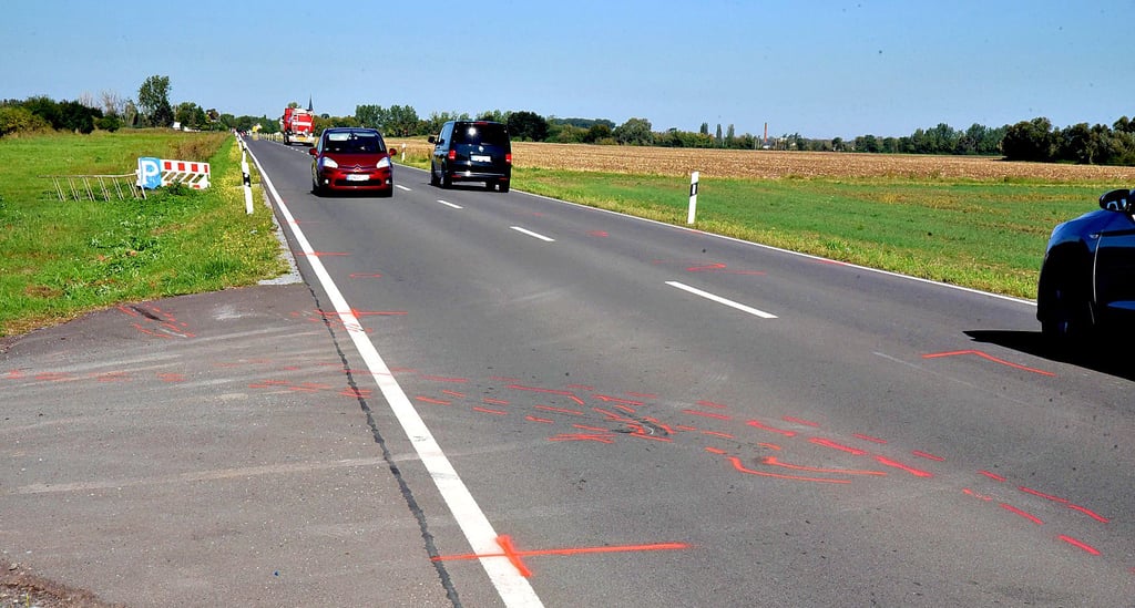 Die roten Markierungen auf Fahrbahn und Rasen markieren den Unfallhergang. Links befindet sich die Einfahrt zum Beachvolleyballplatz.