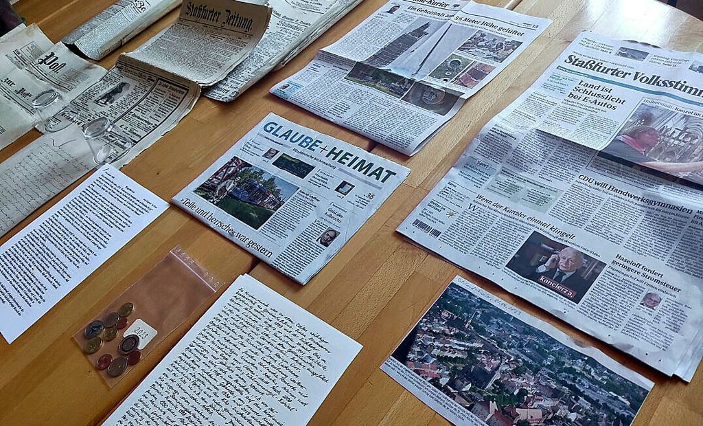 Neues Material für die Zeitkapsel. Neben Geldmünzen sind auch Zeitungsausschnitte zu den historischen Dokumenten hinzugekommen.
