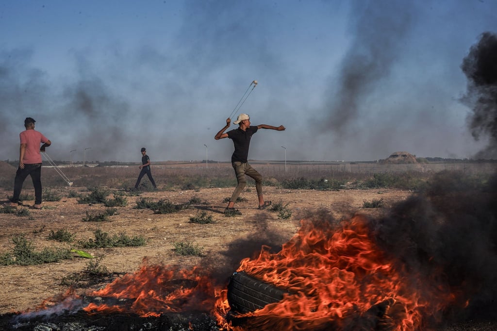 Ein palästinensischer Jugendlicher schleudert in Richtung israelischer Truppen.