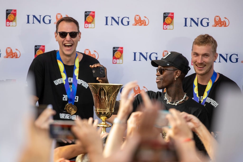 Kapitän Dennis Schröder hält beim Empfang den Pokal. Hinter ihm stehen Johannes Voigtmann und Niels Giffey.