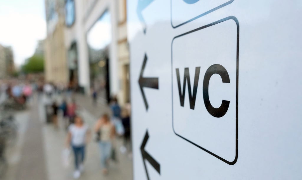 Ein Schild weist in der Innenstadt den Weg zu einer öffentlichen Toilette.