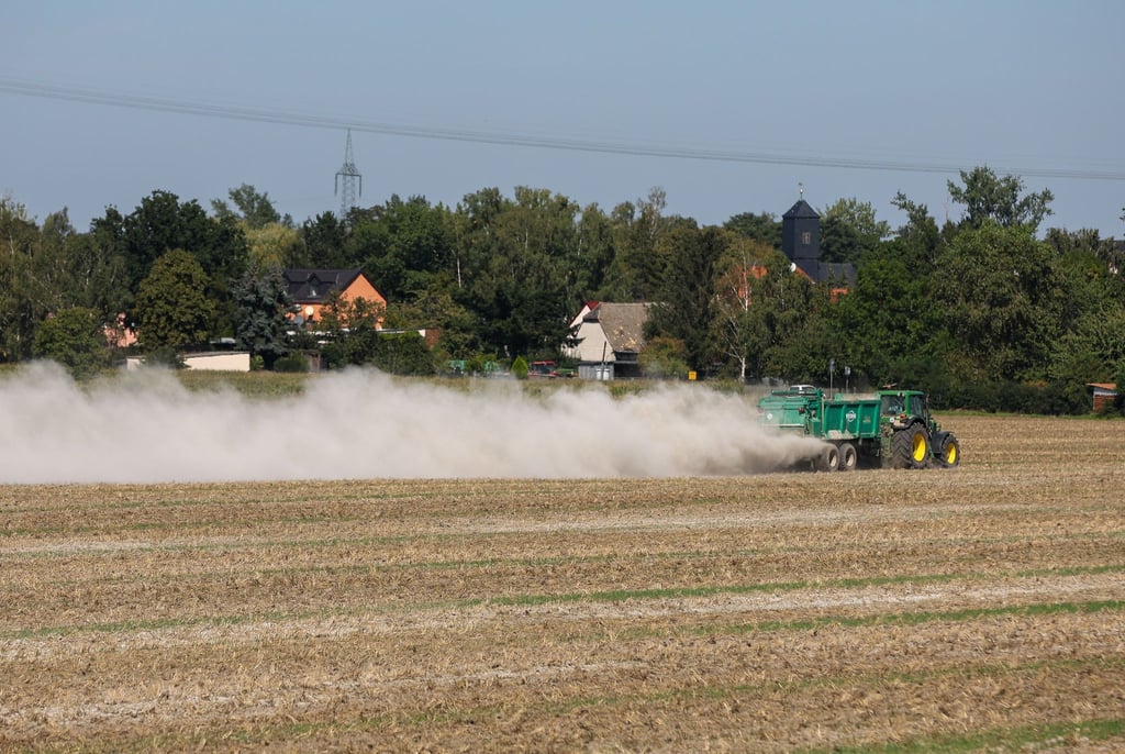 Ein Landwirt bringt zur Bodenverbesserung Kalk auf einem Feld aus.
