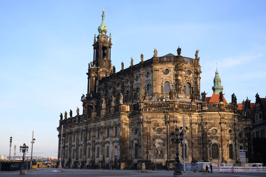 Passanten gehen vor der Dresdner Kathedrale über den Schlossplatz.