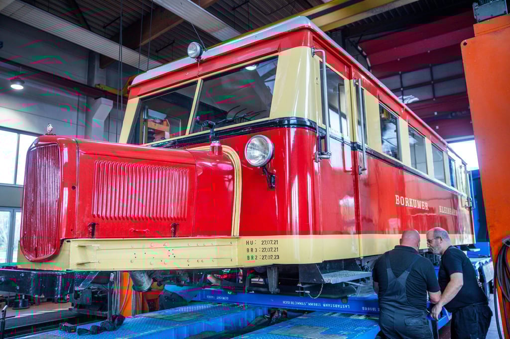 Mitarbeiter der Kleinbahn Molli entladen den Triebwagen T1 der Borkumer Kleinbahn von einem Tieflader und stellen das sogenannte „Schweineschnäuzchen" auf das Schmalspurgleis.