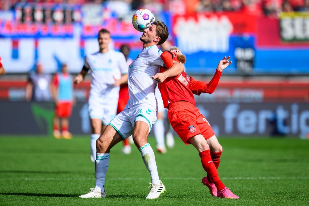 Bremens Niklas Stark (l) in Aktion gegen Heidenheims Jan-Niklas Beste (r).