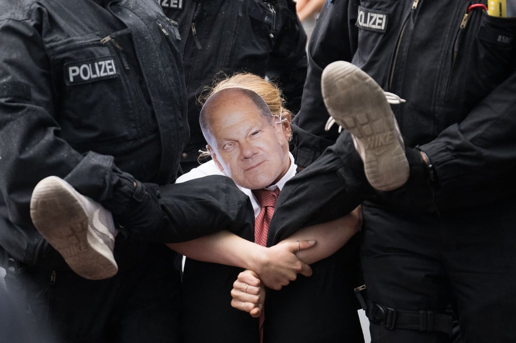 Polizisten tragen während eines Protestmarsches der Klimaschutzgruppe Letzte Generation eine Teilnehmerin von der Straße.