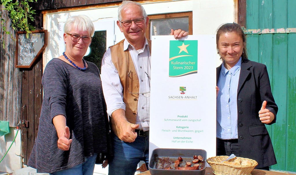Projektmanagerin Anne Hanika (r.) von der Agrarmarketinggesellschaft Sachsen-Anhalt überreicht den „Kulinarischen Stern 2023“ an Jutta und Jochen Dettmer vom Hof an der Eiche in Belsdorf.