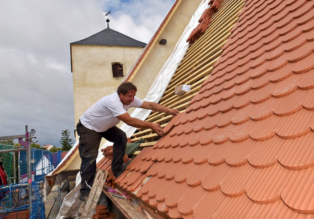Echte Handarbeit: Thomas Aderhold von der Eisleber Dachdeckerfirma Hildebrandt bestückt das Kirchendach mit neuen Ziegeln.