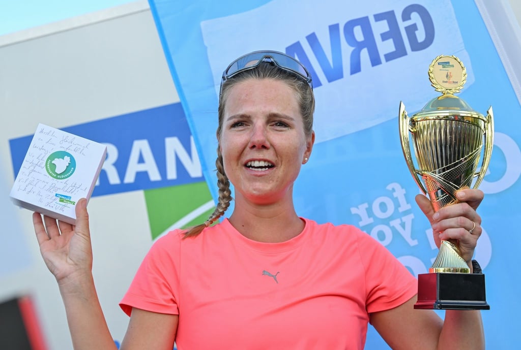 Joyce Hübner, Sportlerin, hält ein Geschenk und einen Pokal der Stadt Frankfurt (Oder) nach ihrem Zieleinlauf der Deutschlandumrundung in den Händen.