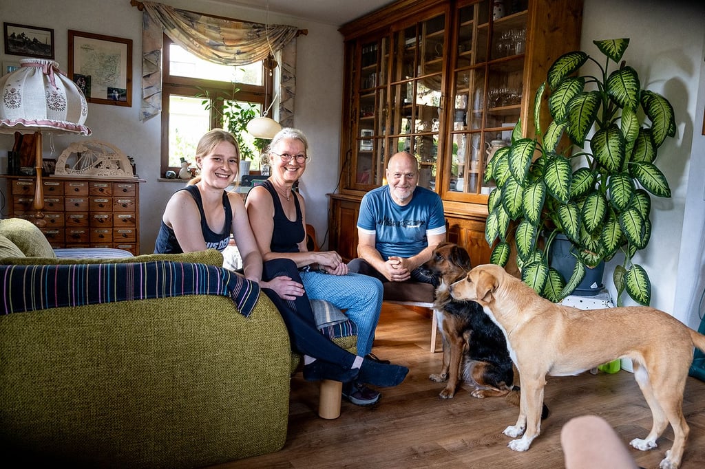 Umgesiedelt: Annette und Michael Großmann sitzen mit Tochter Henrike im Wohnzimmer. Im Hintergrund steht Großvaters alte Backstuben-Vitrine, die sie mitgenommen haben.