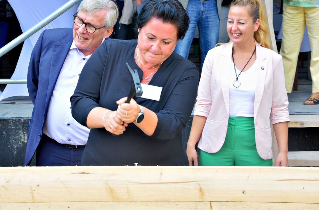 Cathleen Bastuck, Einrichtungsleiterin, zeigt vollen Einsatz beim Richtfest und setzt den Nagel gekonnt in den Holzbalken.