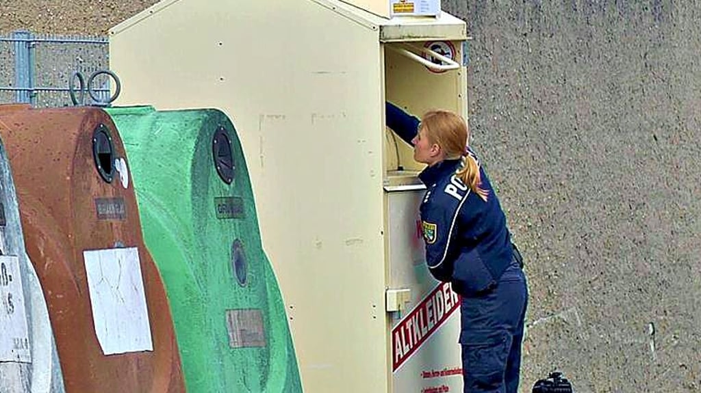 Eine Polizistin vor dem Altkleidercontainer in Tangerhütte, in dem das tote Baby gefunden wurde.