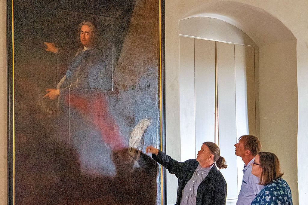 Museumsdirektor Jörg Peukert (l.), Museumsmitarbeiterin Mandy Wignanek und Falk Gast vom Neuenburg-Verein vor dem restaurierten Gemälde, das August den Starken als polnischen König zeigt.