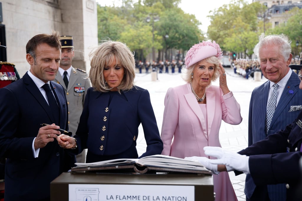 Präsident Emmanuel Macron (l-r) und und seine Ehefrau Brigitte Macron sowie Königin Camilla und König Charles III. von Großbritannien tragen sich während einer Zeremonie am Triumphbogen in Paris ins Goldene Buch ein.