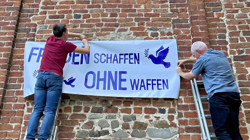 Christoph (links) und Andreas Große bringen an der Stadtkirche von Jerichow am Donnerstagabend dieses Banner an.