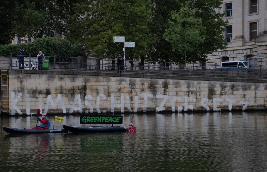 Aktivisten von Greenpeace haben an die Kaimauer unterhalb des Reichstages das Wort "Klimaschutzgesetz" geschrieben.