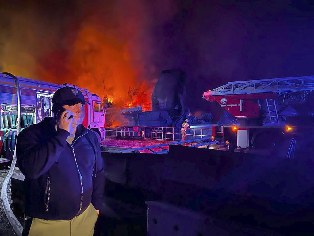 Rauch und Flammen steigen aus einer brennenden Werft auf der Krim auf, während der von Moskau ernannte Gouverneur Sewastopols, Michail Raswoschajew, am Telefon spricht. Er bestätigte den Beschuss des Flottenhauptquartiers auf seinem Telegram-Kanal.