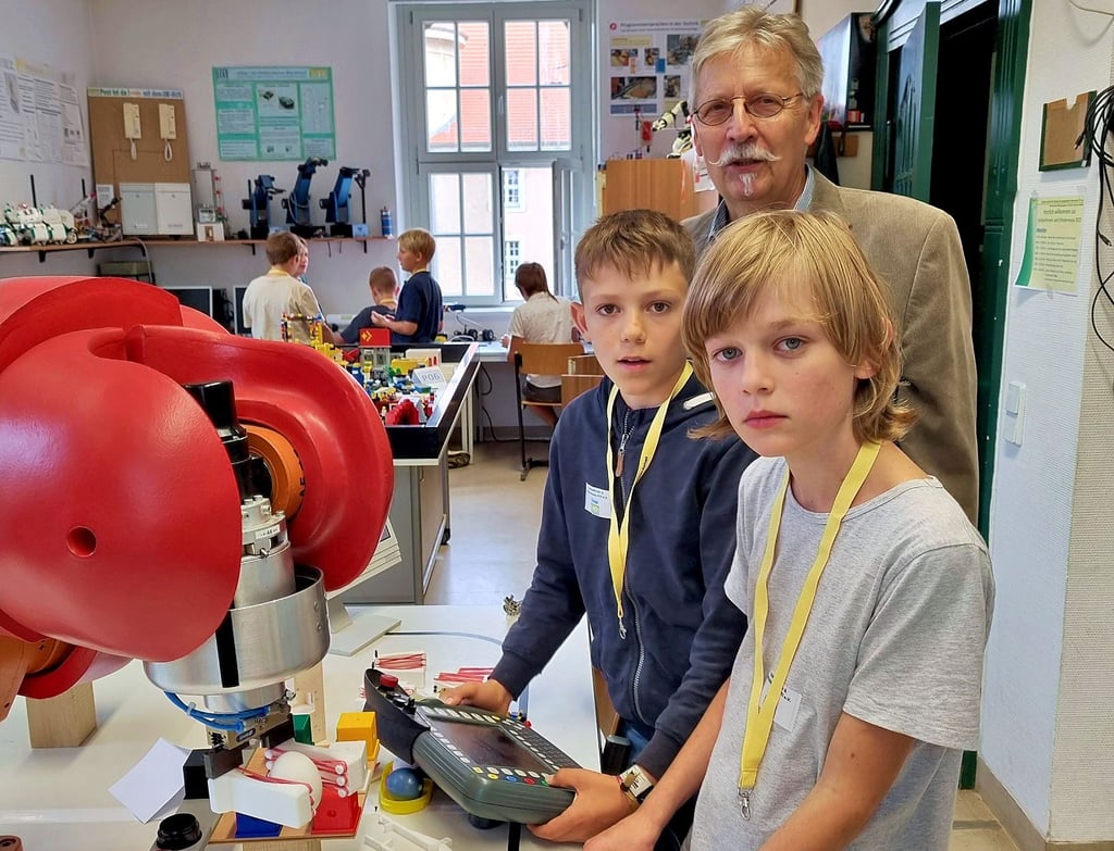 Dem Industrieroboter im Schüler-Institut haben Elio (vorn) und Elmar das Eiergreifen und den Eiertransport beigebracht. Den Roboter in Gang bringen dürfen sie jedoch nur im Beisein von Hannes König (hinten).