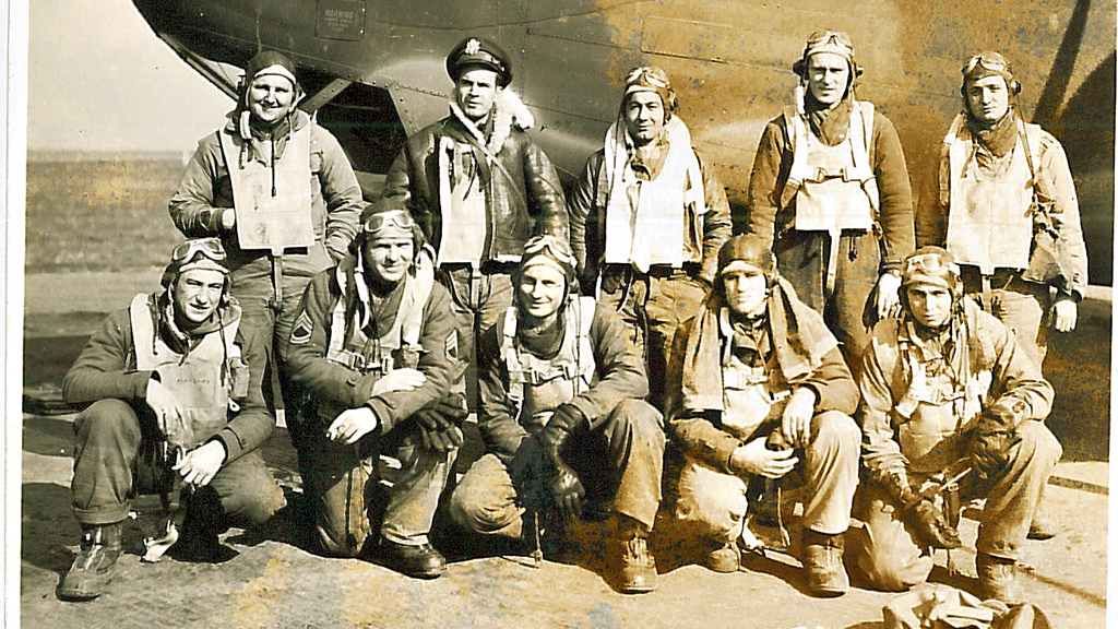 Zehn junge Männer lächeln 1944 bei Sonnenschein in die Kamera. Mit dem Flugzeug im Hintergrund werden sie kurz darauf zu einem Kriegseinsatz gegen Deutschland aufbrechen, den keiner von ihnen überleben wird. Bei Salzwedel wurde ihr Flugzeug beschossen, explodierte und stürzte ab.
