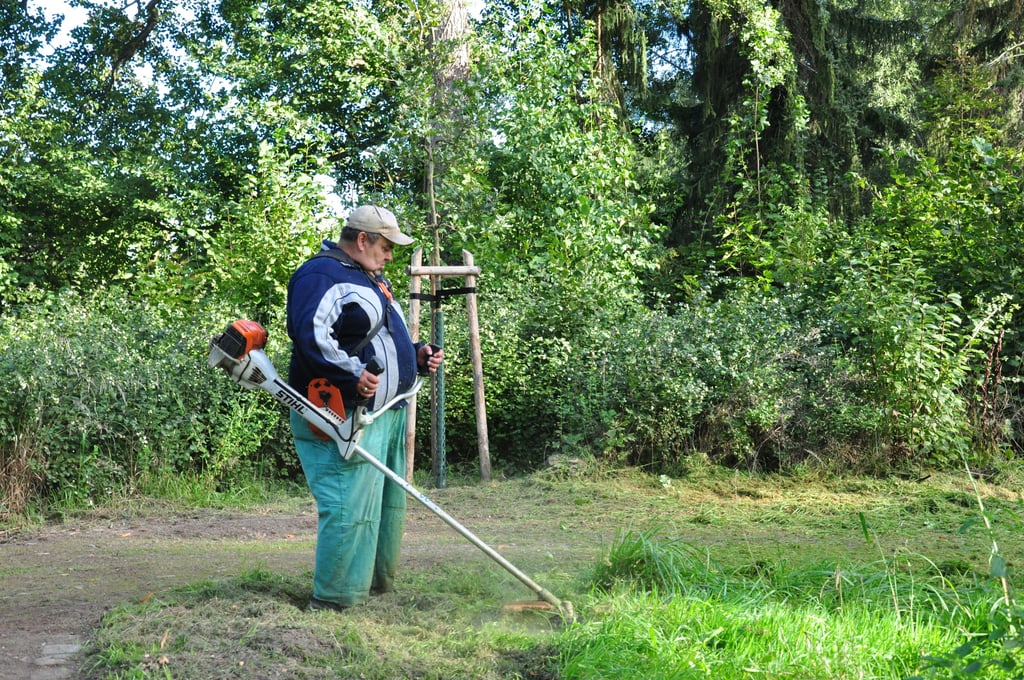 Heino Bergmann, der über eine vom Jobcenter geförderte Maßnahme tätig ist, mäht im Kurpark Kalbe die Seitenbereiche der Wege.