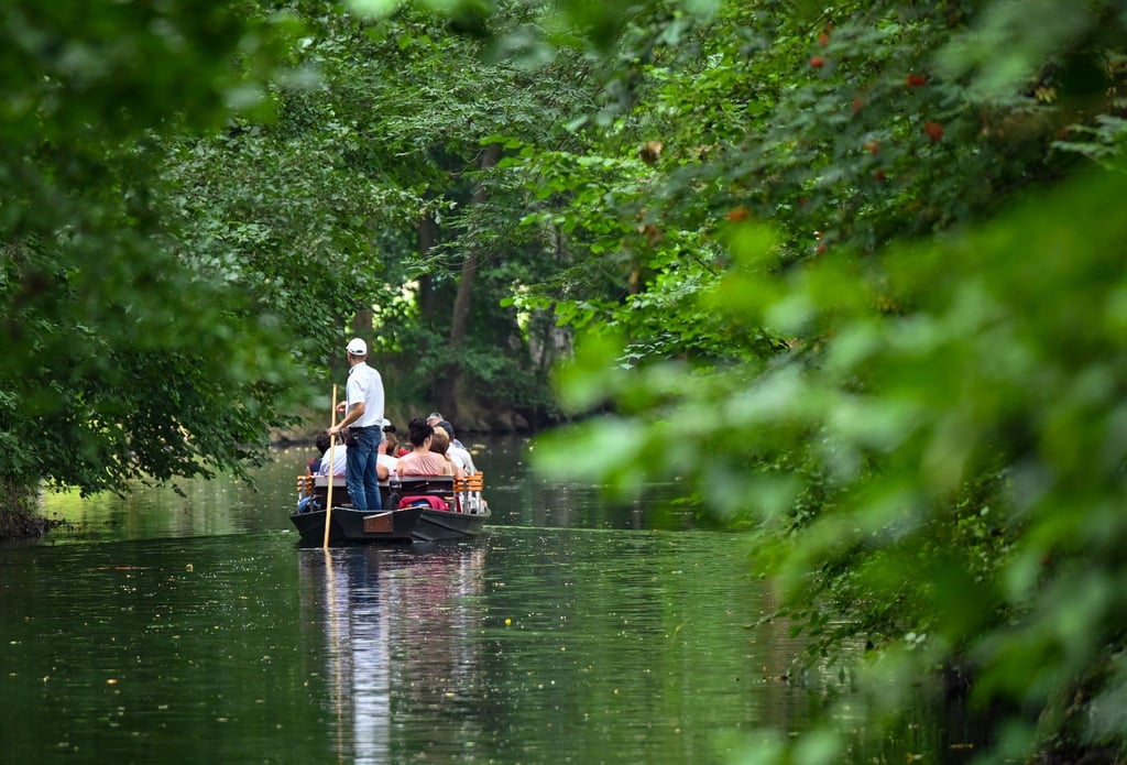 Ein Fährmann ist mit einem Kahn mit Touristen auf einem Fließ (Wasserweg) im Spreewald unterwegs.