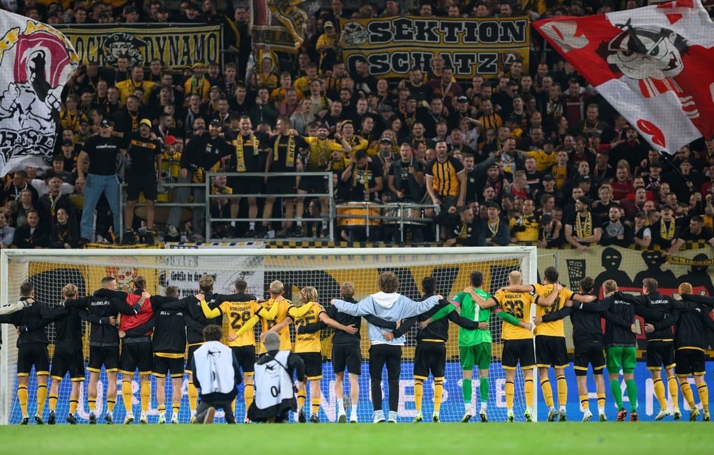 Dynamos Spieler jubeln nach dem Sieg vor dem K-Block.