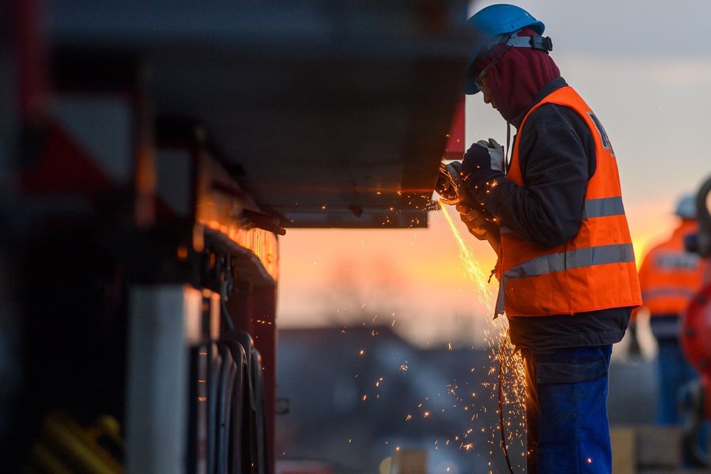 Ein Arbeiter führt auf einer Baustelle Schweißarbeiten an einer Brücke aus.