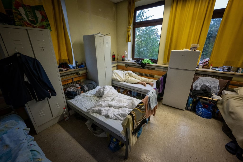 Ein Mann liegt in eine Asylunterkunft in seinem Bett.