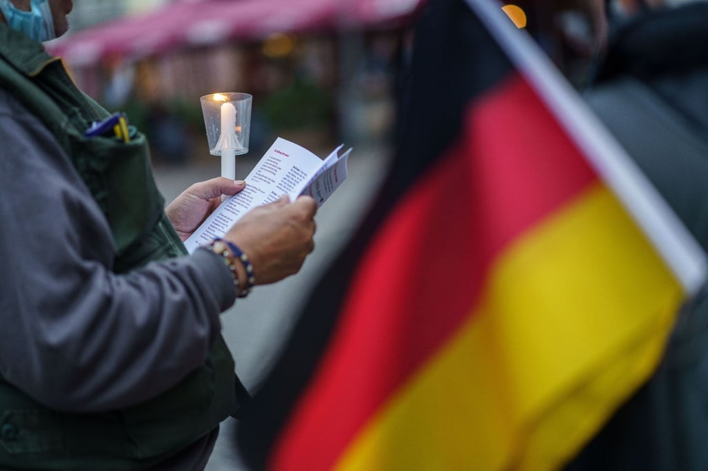Am Tag der Deutschen Einheit stehen abends Menschen auf dem Römerberg und singen.