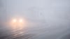 Autos fahren bei dichtem Nebel über eine Straße.