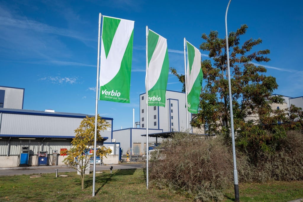 Vor einem Teil der Verbio Vereinigte BioEnergie AG-Anlage wehen Flaggen mit dem Logo des Unternehmens.