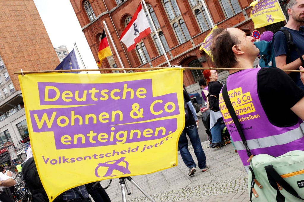 Ein Demonstrant hält eine Fahne mit der Aufschrift „Deutsche Wohnen und Co enteignen“.