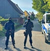Vermummte Polizisten sichern in Kupferzell (Baden-Württemberg) eine der  Durchsuchungen ab.