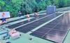 Mehrere Photovoltaik-Module installieren die Fachleute auf dem Dach des Kabinenbahn-Gebäudes. 