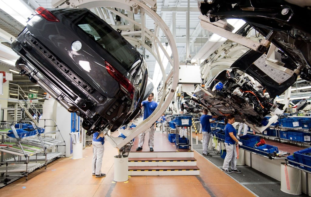 Ein neuer Volkswagen Golf 8 (l) schwebt an einer Produktionslinie im VW Werk.