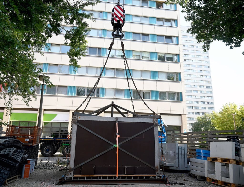 Ein Kran transportiert eine mittelalterliche Latrine in einer Box an ihren endgültigen Standort auf der Fischerinsel.