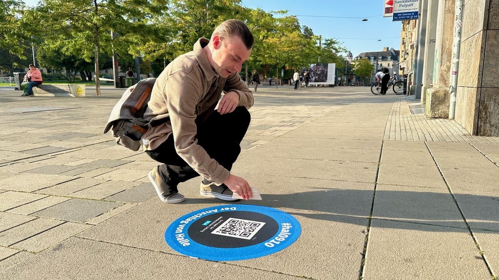 MZ-Reporter Denny Kleindienst bringt den Bodenaufkleber für den dritten Serienteil, den er geschrieben hat, am Steintor an.