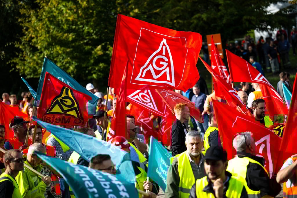 Mit Plakaten und Fahnen stehen die Teilnehmer einer Kundgebung vor der Hauptverwaltung vom Stahlhersteller Arcelormittal.