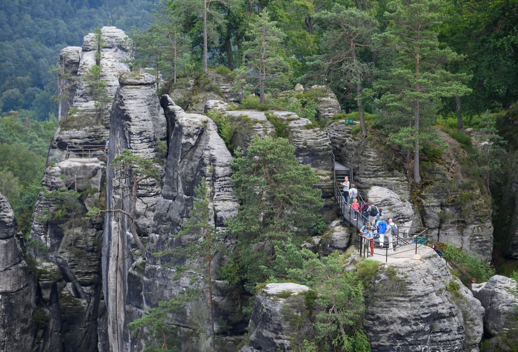 Touristen stehen im Nationalpark Sächsische Schweiz auf einer Aussichtsplattform der Felsenburg Neurathen.