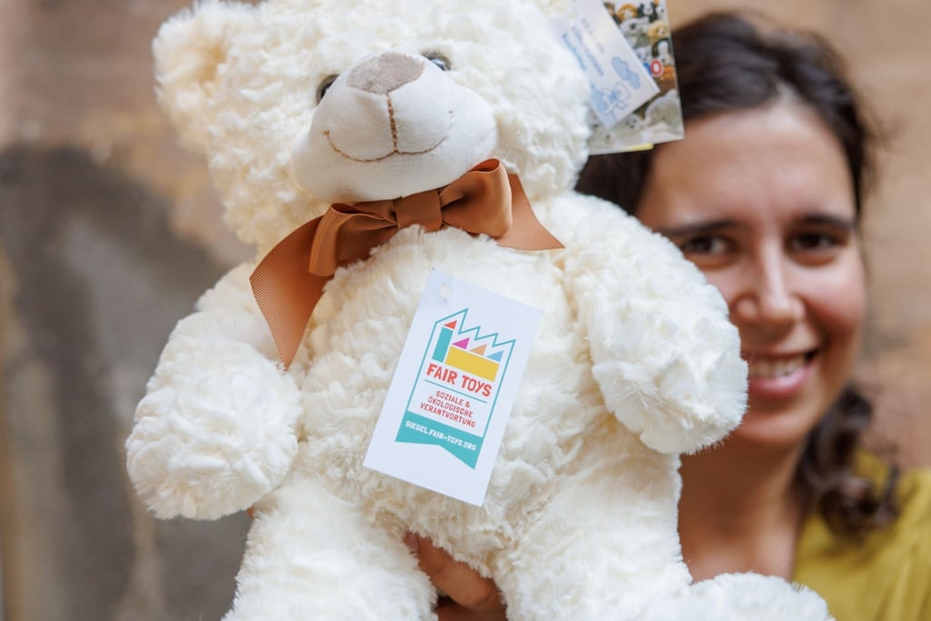 Eine Mitarbeiterin des Plüschtierherstellers Heunec präsentiert einen Stoffteddy, der mit dem Siegel der Fair Toys Organisation gekennzeichnet ist.