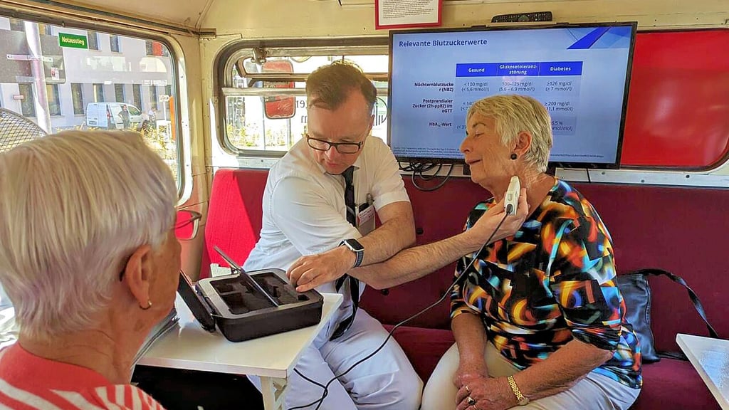Dr. Cornelius Werner, Chefarzt der Neurologie und Geriatrie im Johanniter-Krankenhaus in Stendal, prüft im Londoner Doppeldecker-Herzbus die Halsschlagader von Ute Brüggemann.