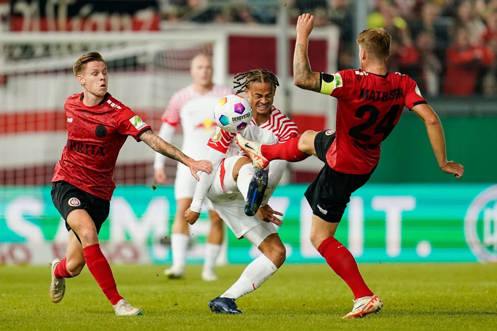 Wiesbadens Julius Kade (l-r), Leipzigs Xavi Simons und Wiesbadens Marcus Mathisen kämpfen um den Ball.