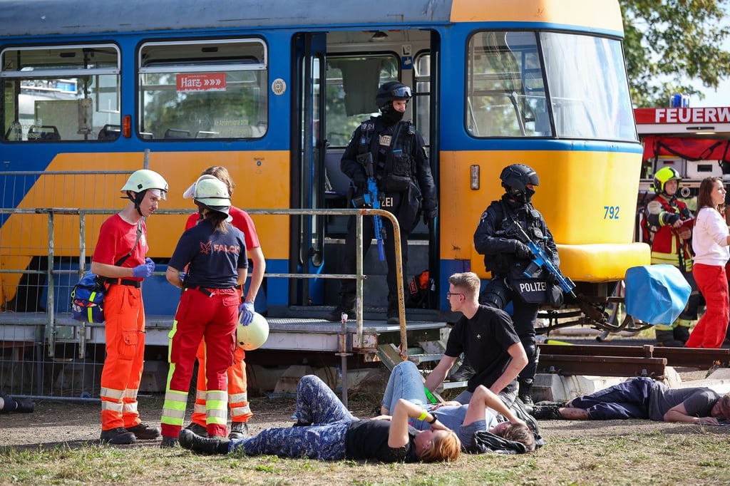 Polizisten sichern während einer Terrorübung eine Straßenbahn während sich Rettungskräfte einen Überblick verschaffen.