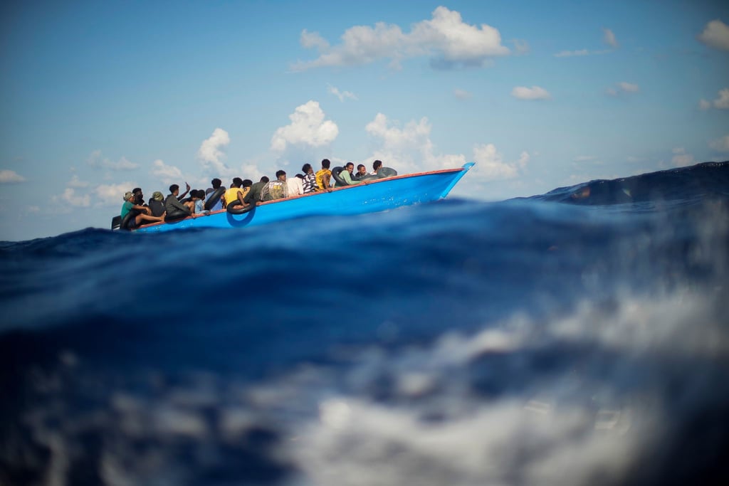 Migranten sitzen in einem Holzboot südlich der italienischen Insel Lampedusa auf dem Mittelmeer.