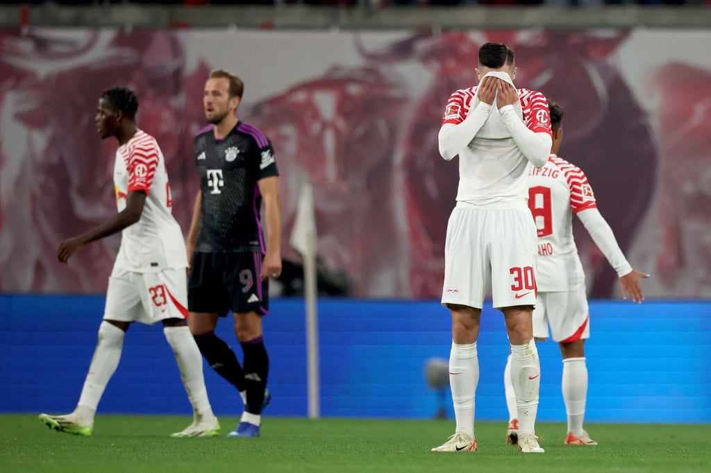 Leipzigs Castello Lukeba (l) und Leipzigs Benjamin Sesko gehen mit Münchens Harry Kane (2.v.l.) nach dem 2:2 Endstand vom Platz.
