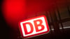 Das Logo der Deutschen Bahn leuchtet an einem Bahnhof hinter einer Ampel.