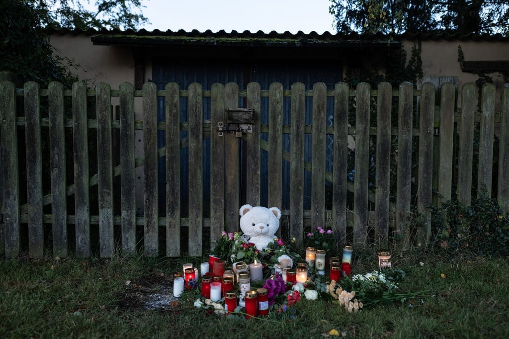 Kerzen, Blumen und ein großer Plüschteddy vor einem Zaun am Fundort der Leiche einer 14-Jährigen.