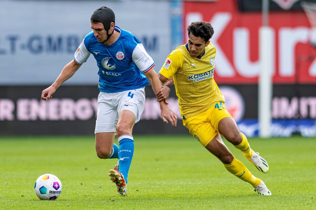 Der Rostocker Damian Roßbach (l) behauptet den Ball gegen den Braunschweiger Johan Gomez.