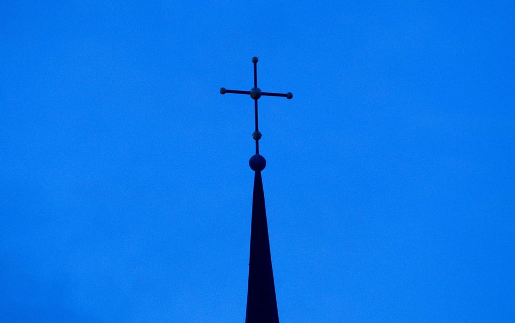 Kreuz einer evangelisch-lutherischen Kirche in der Abenddämmerung.